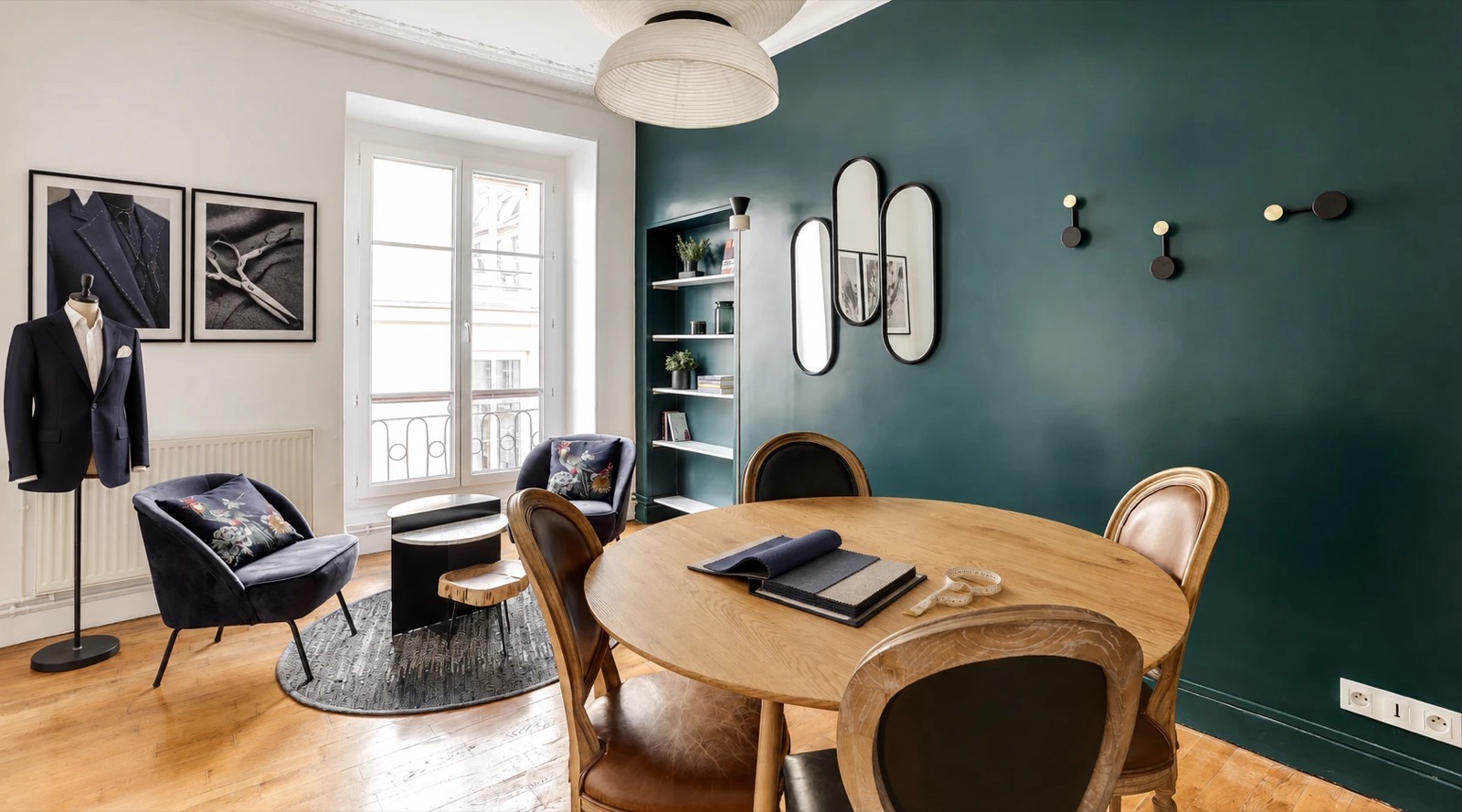 Le salon Louvois : mur vert canard, table ronde de sélection des tissus et fauteuils en velours